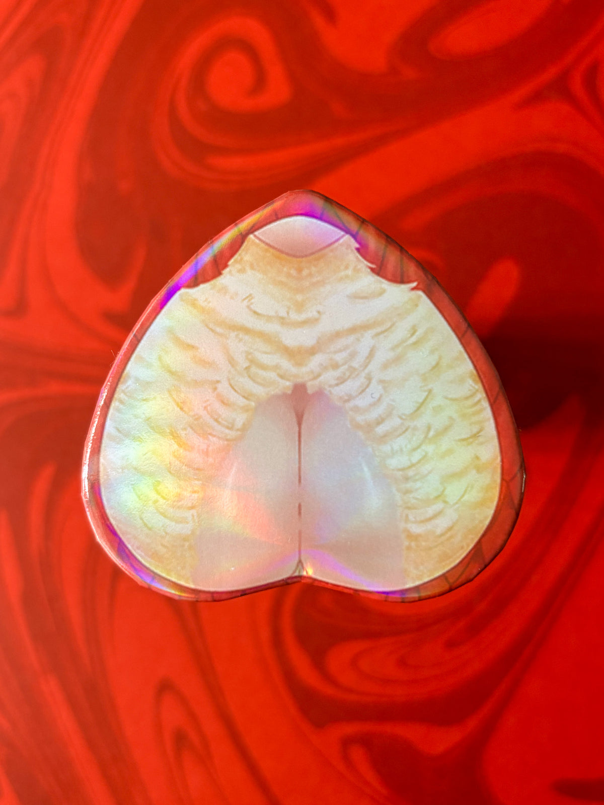 A heart-shaped product with a holo sheen, predominantly white and pink in color. Displays Falin from anime Dungeon Meshi (Delicious In Dungeon)
