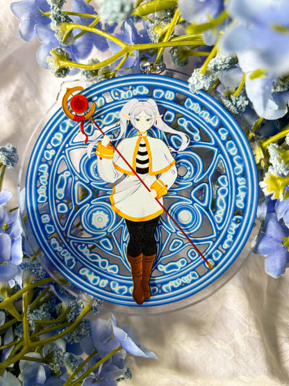 Acrylic charm featuring Frieren in a white and black outfit holding a red staff, with magic spell in the background.