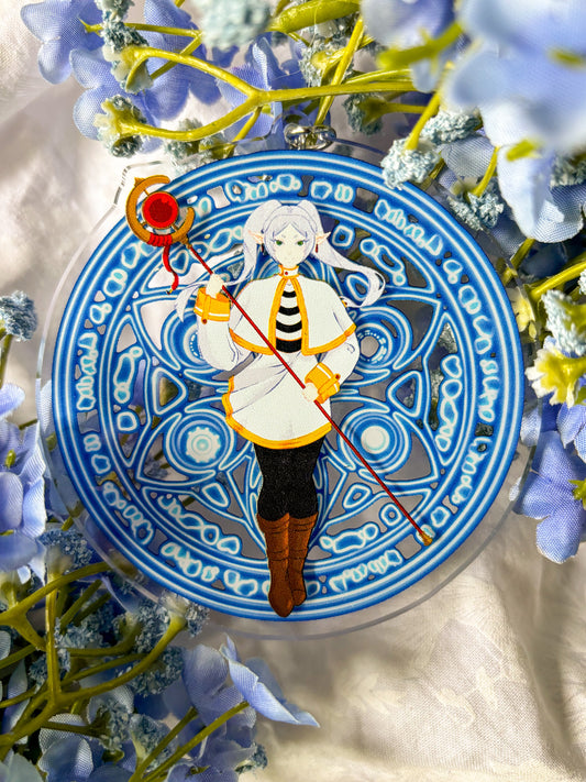 Acrylic charm featuring Frieren in a white and black outfit holding a red staff, with magic spell in the background.