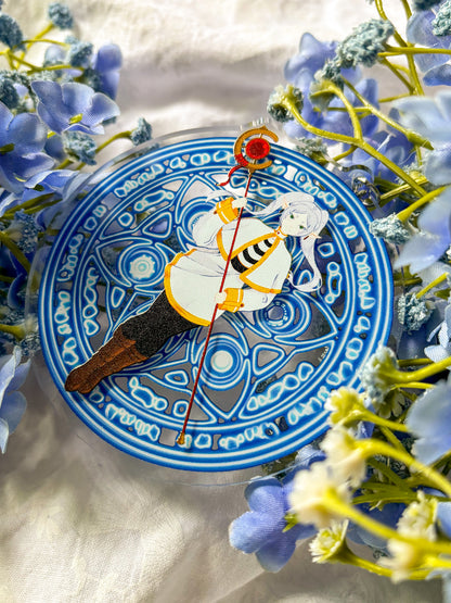 Acrylic charm featuring Frieren in a white and black outfit holding a red staff, with magic spell in the background.