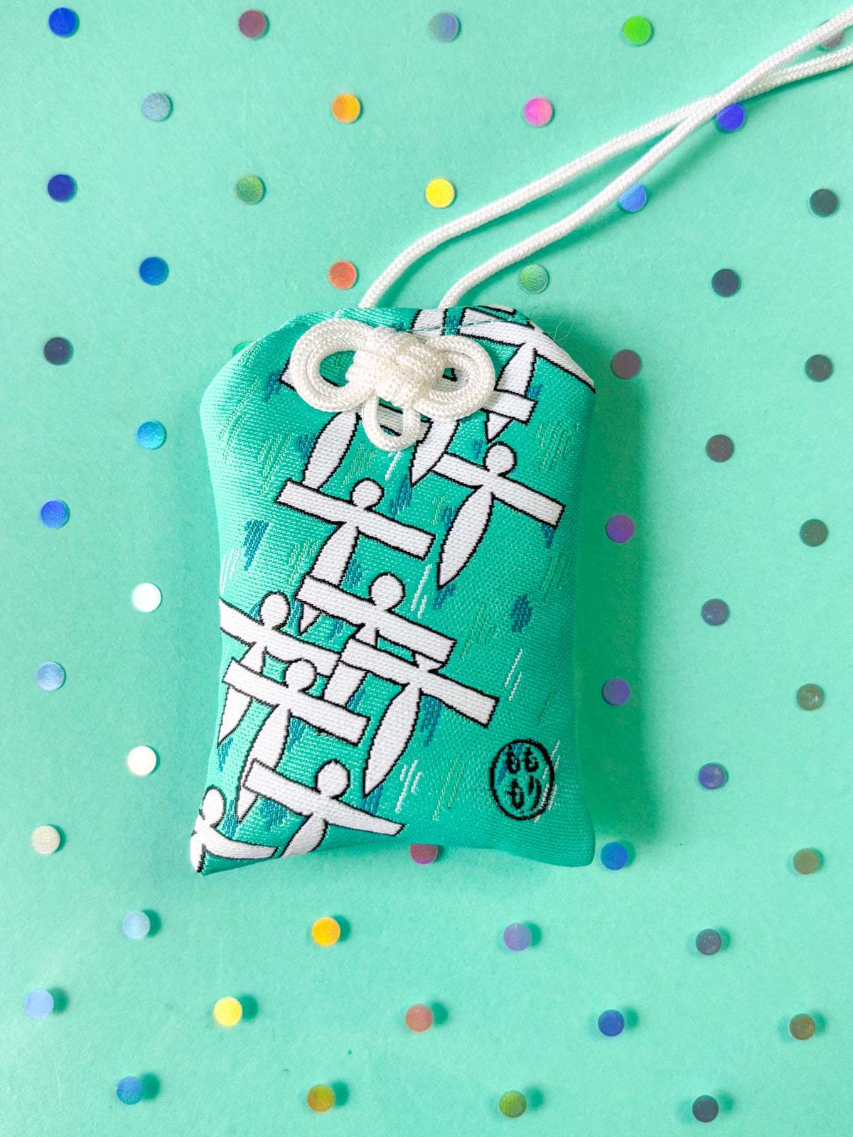 Japanese good luck charm (omamori) based on the Studio Ghibli movie Spirited Away. Based on the Paper Spirit characters. This is a teal (green-blue) fabric charm that displays the Paper Spirits flying over water.