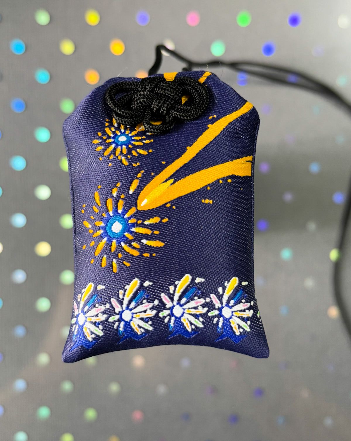 Japanese good luck charm (omamori) based on the Studio Ghibli movie Howl's Moving Castle. Based on the Star Children characters. Charm shows colorful firework-like designs with the Star Children lining the bottom.